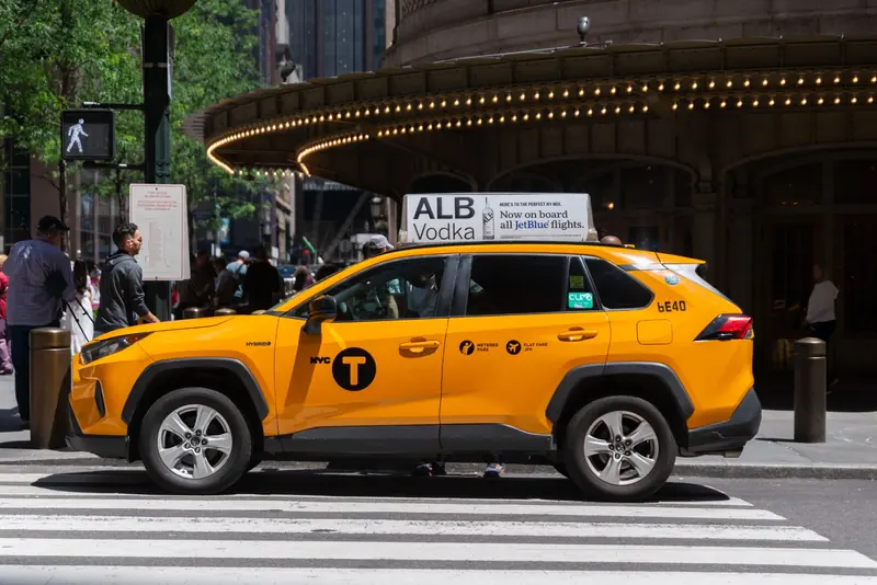 A yellow cab with a static top for a spirits brand outside a theater