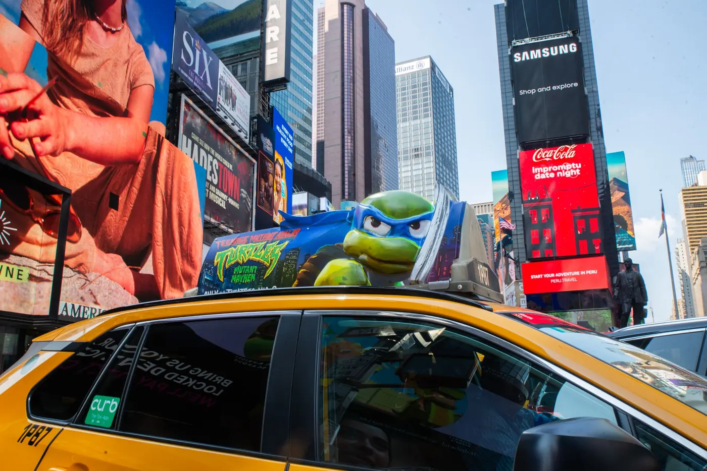 A sculpted taxi top rising above the billboards of Times Square