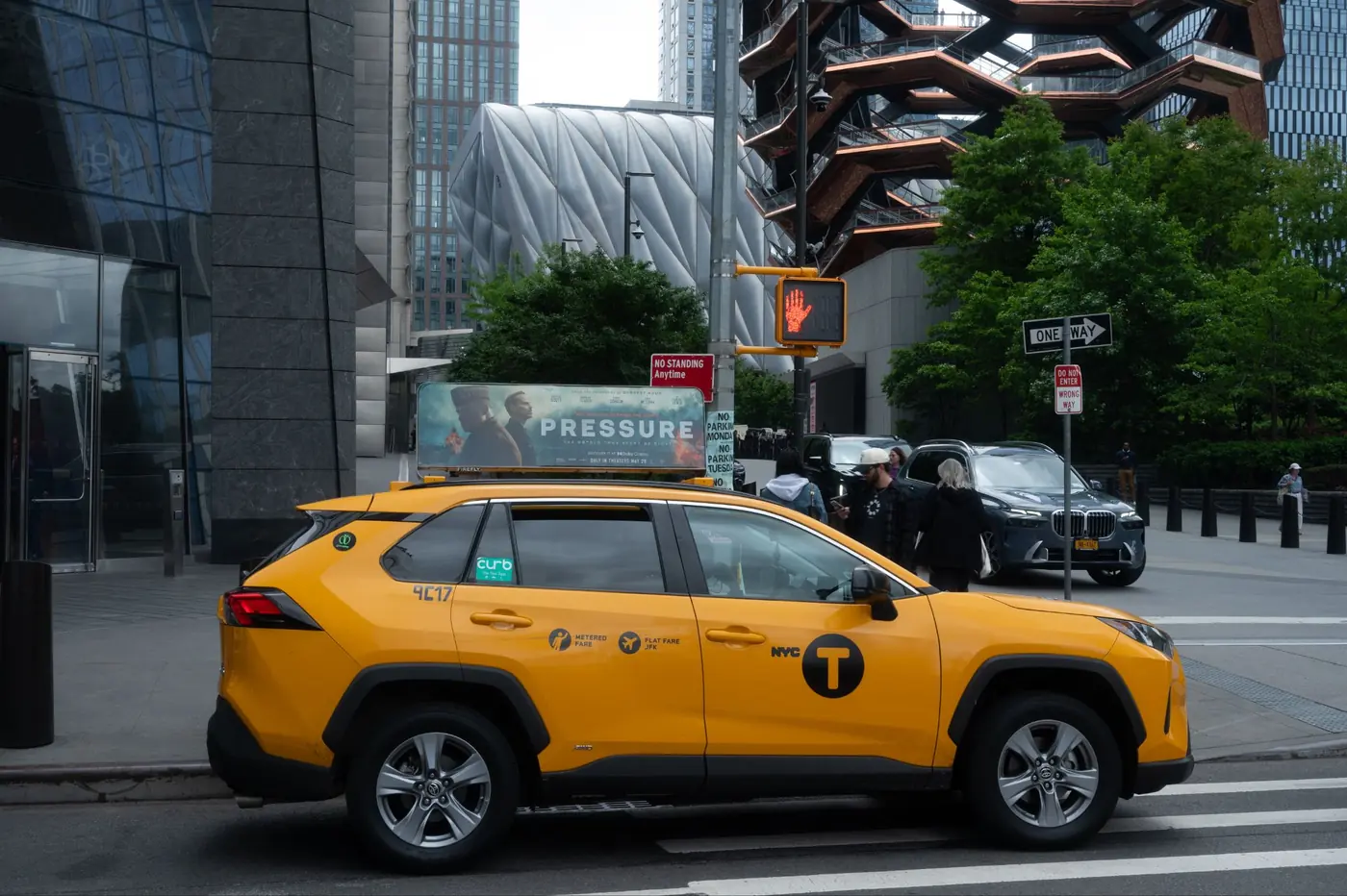 A yellow cab with a static top near Hudson Yards