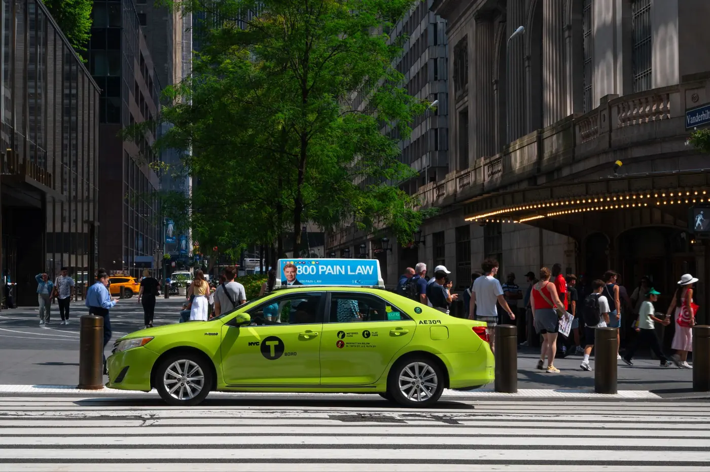 A green borough cab with a static top passing a Manhattan crosswalk