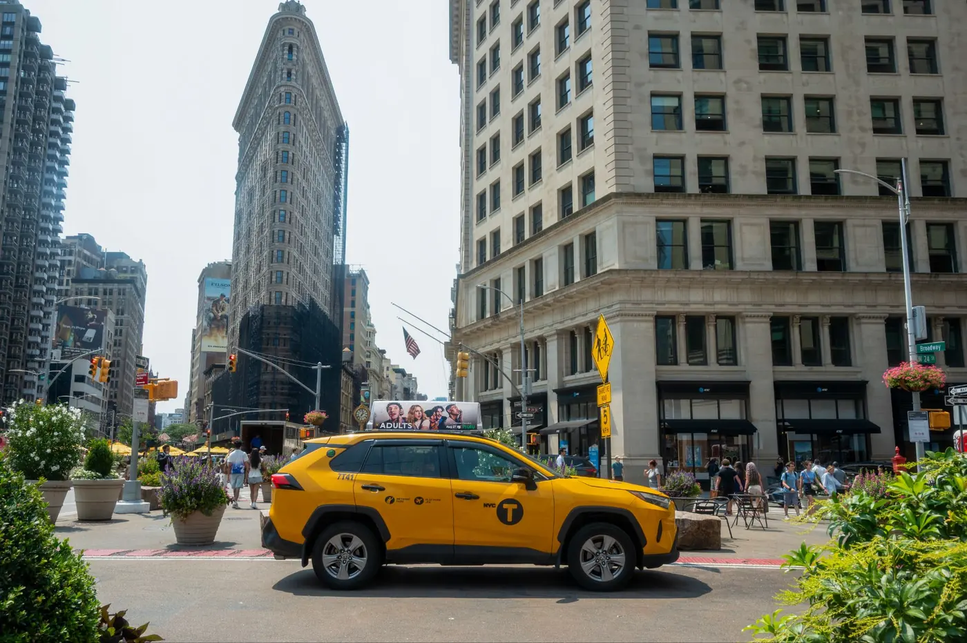 A yellow cab with a static top in front of the Flatiron Building
